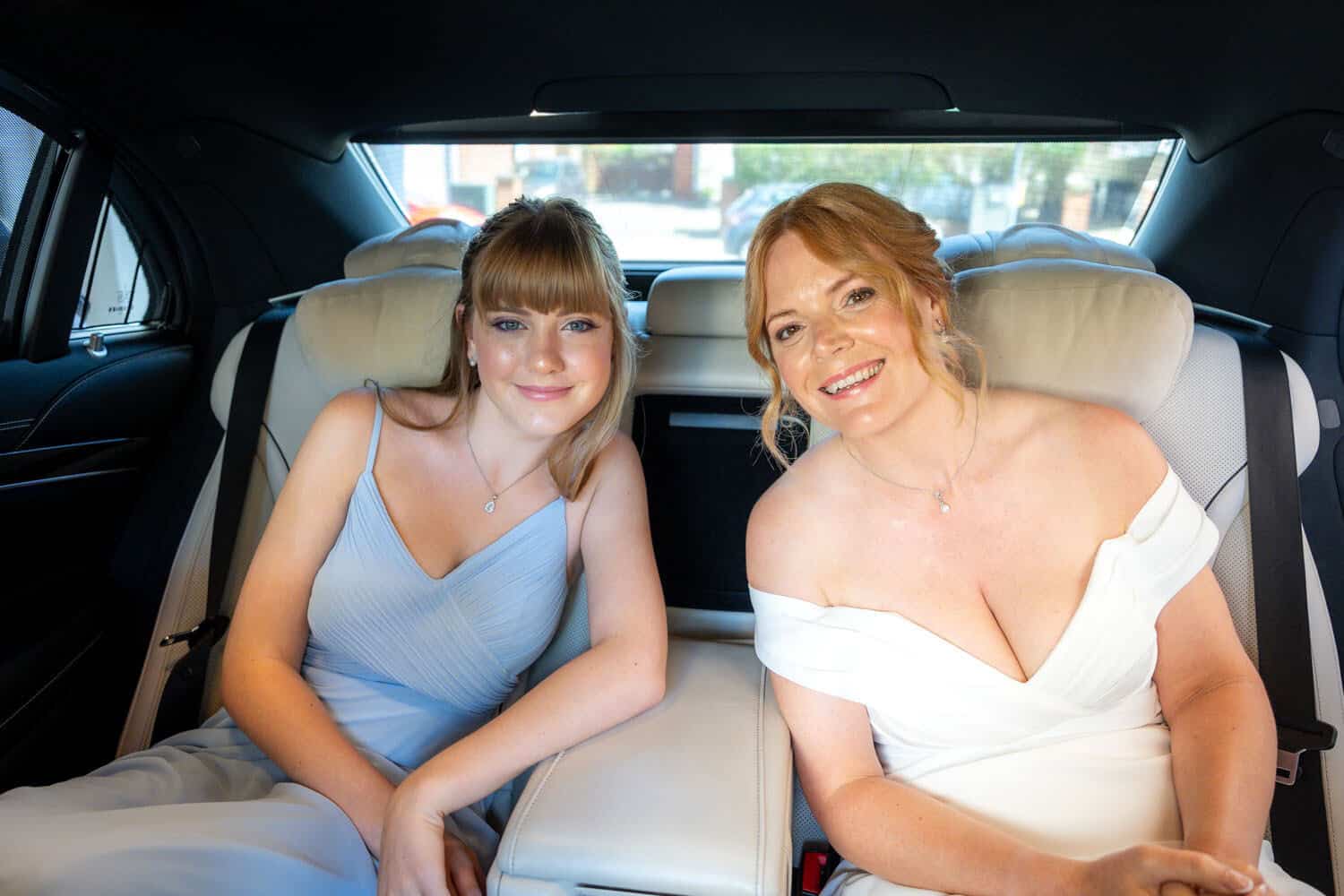 Two smiling women in car seat on wedding day by Southampton wedding photographer John Watson