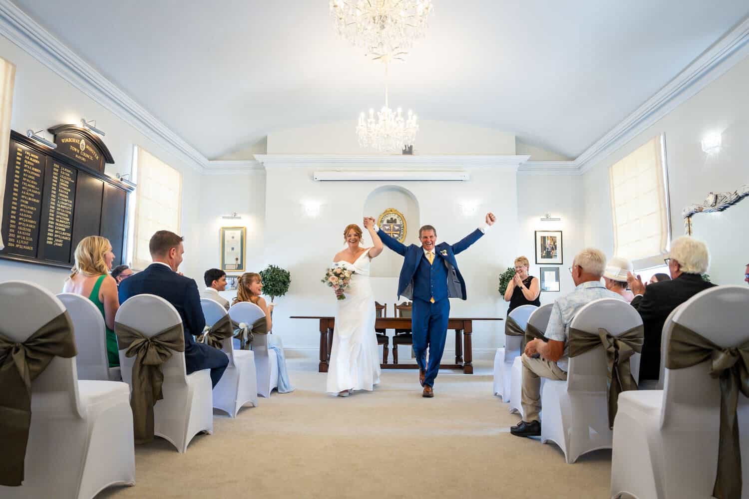 Bride and groom celebrating in a bright ceremony hall by Southampton wedding photographer John Watson
