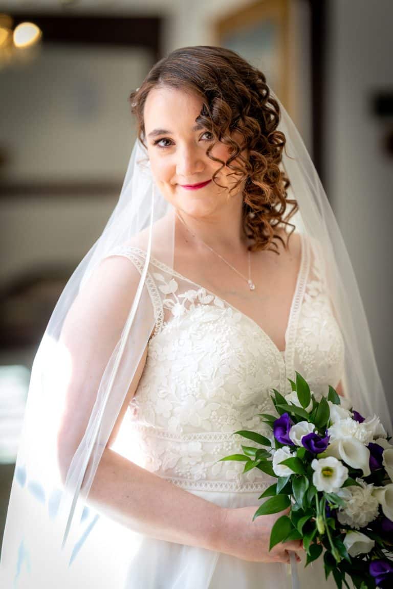 Bride in elegant lace dress holding a bouquet by Southampton wedding photographer John Watson