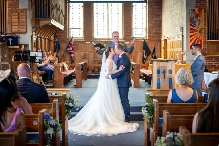 Bride and groom first kiss in church ceremony by Southampton wedding photographer John Watson