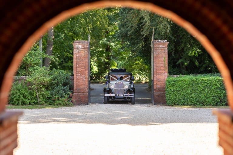 Classic car arriving at wedding venue entrance by Southampton wedding photographer John Watson
